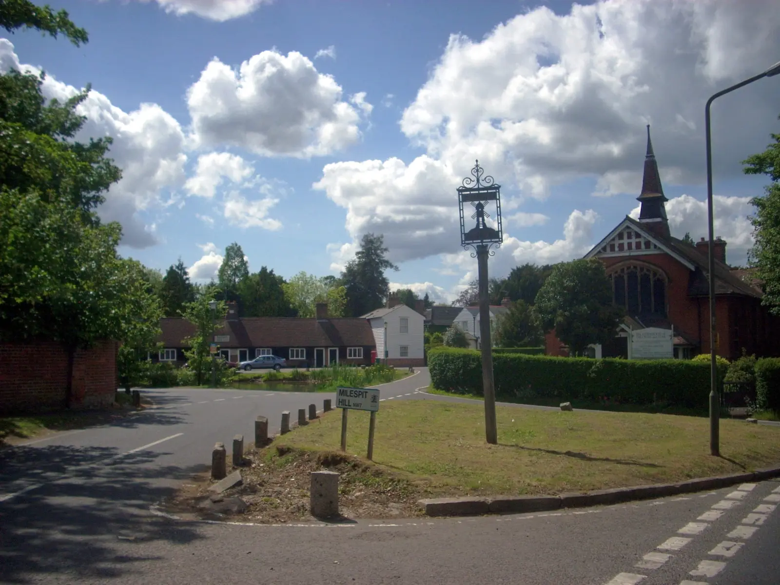 Mill Hill Village: a quiet lane, village sign and church among trees