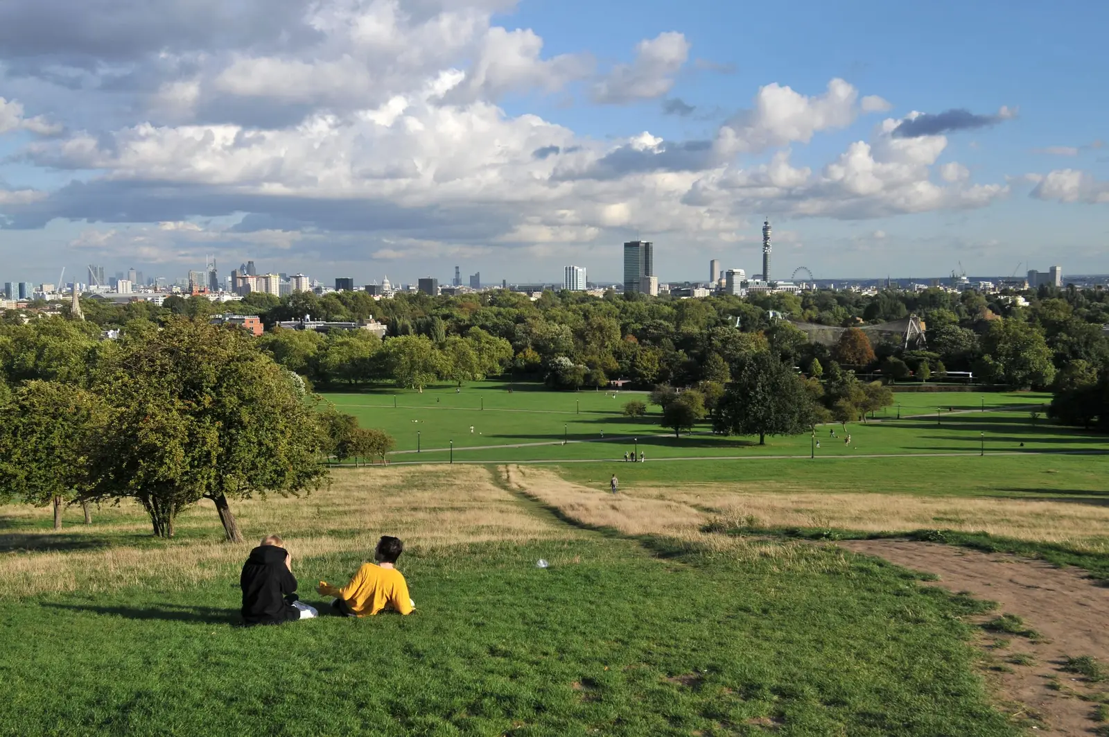 The grassy slope of Primrose Hill with people relaxing in the sun
