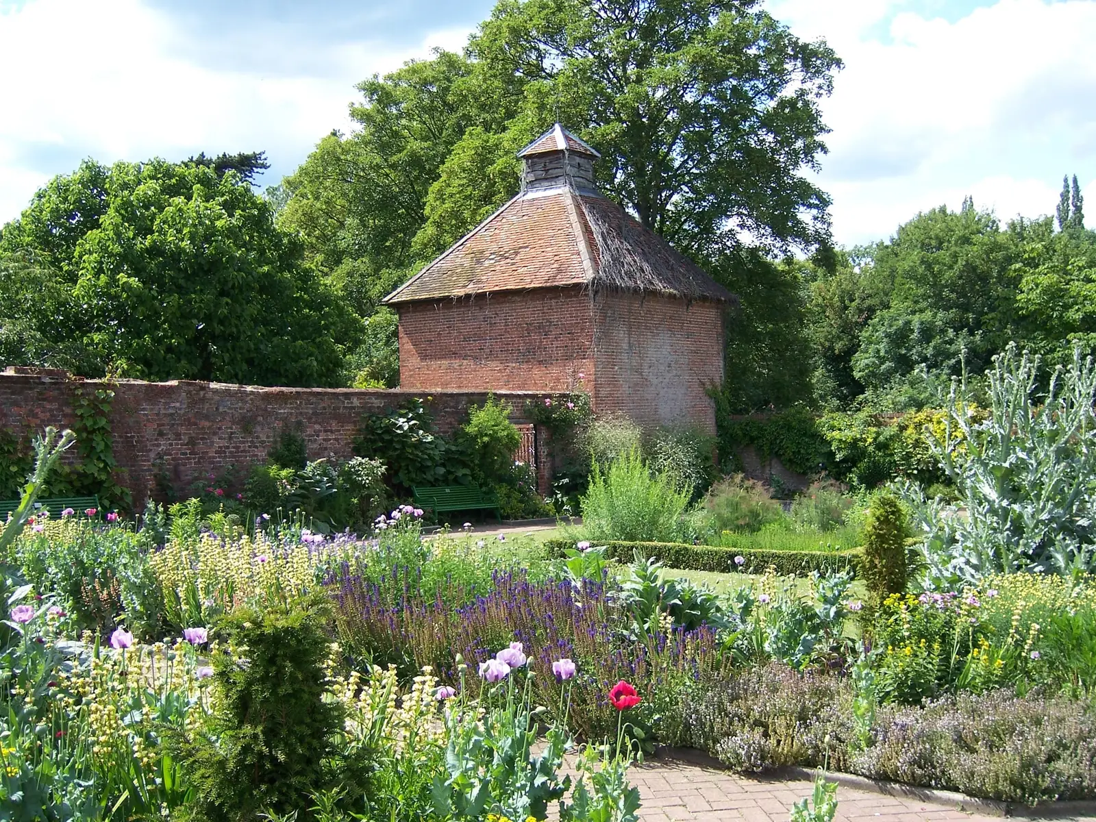 The red-brick dovecote in Eastcote House Gardens behind flowering borders