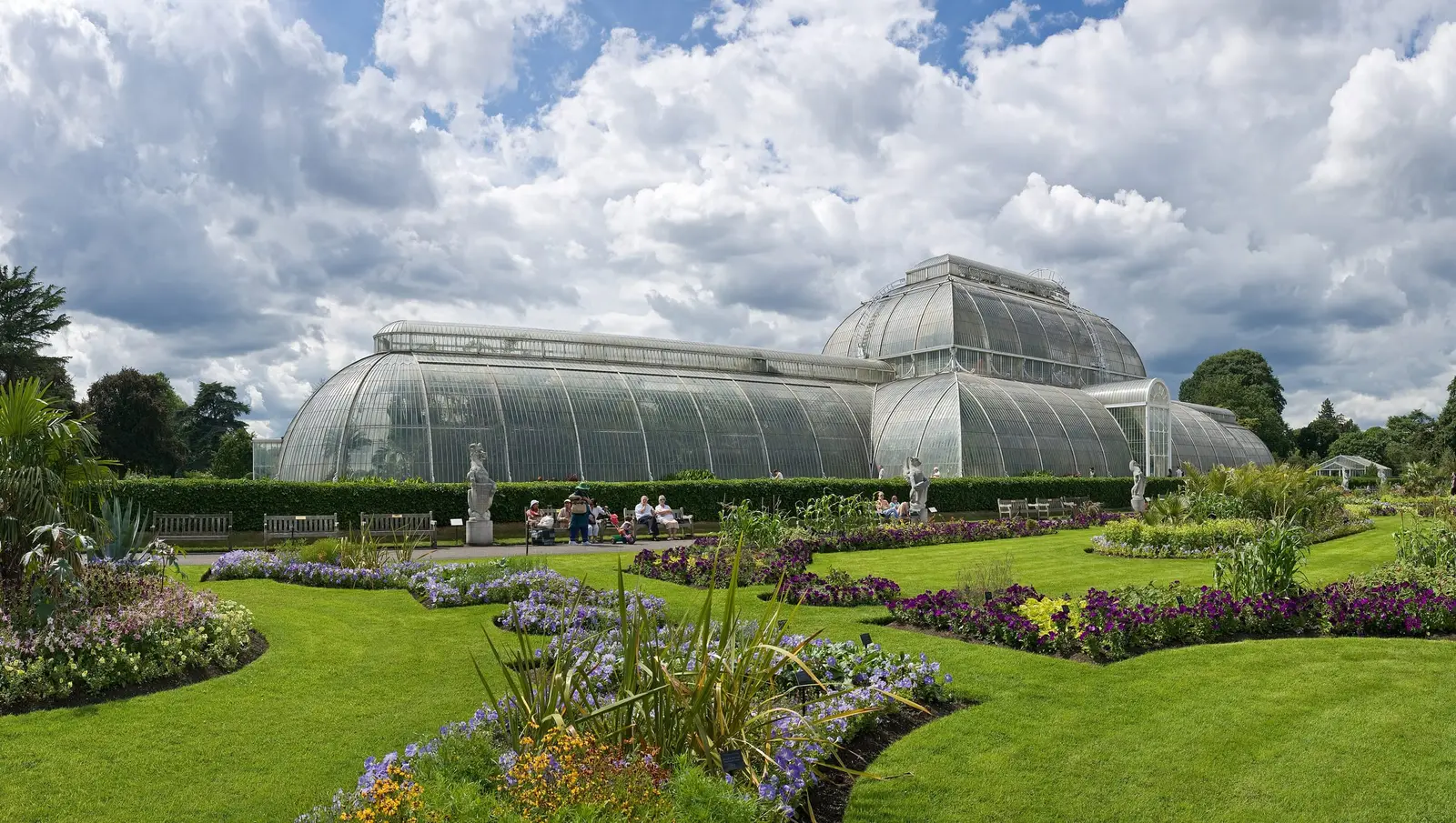 The Palm House at Kew Gardens beyond flower beds